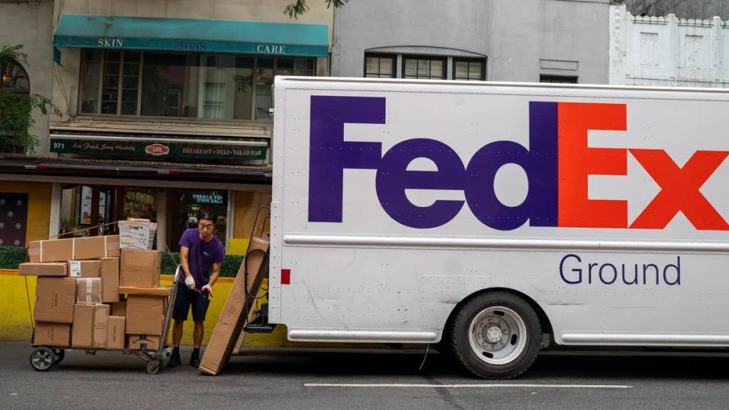 FedEx Ground delivery driver unloading packages from truck on busy city street with hand truck Wallpaper