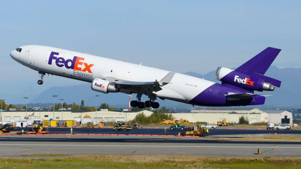 FedEx Express MD-11F cargo plane N642FE taking off under clear blue skies at airport runway Wallpaper