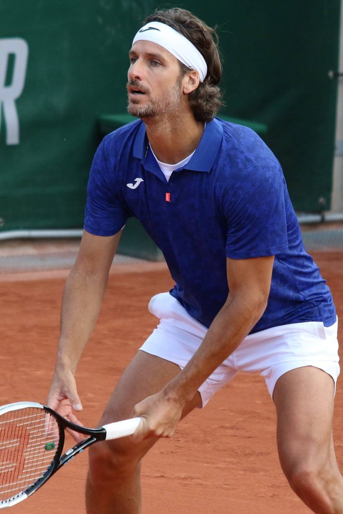 Tennis player Feliciano López in blue polo ready to strike on red clay court at Roland Garros Wallpaper