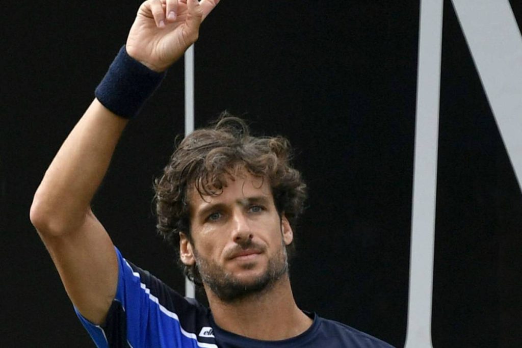 Tennis star Feliciano López in blue raising arm in triumph dark Grand Slam backdrop wallpaper