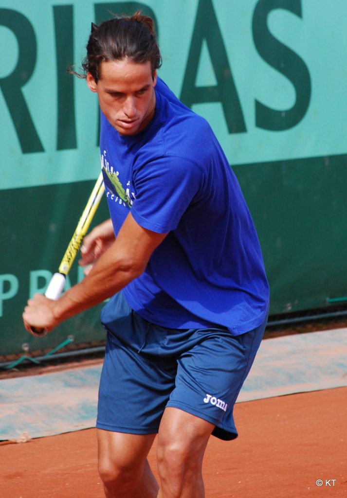 Tennis pro Feliciano López in blue shirt hits shot on Roland-Garros red clay with BNP Paribas background Wallpaper