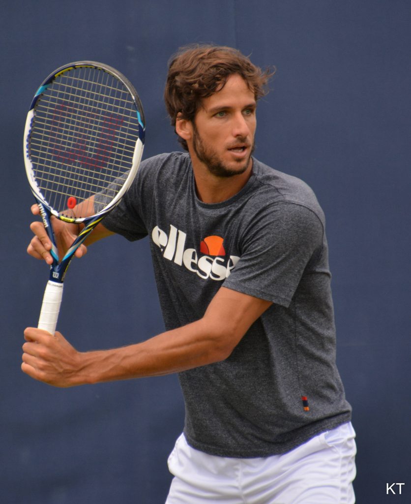 Feliciano López in grey Ellesse shirt holding Wilson racket on blue tennis court wallpaper
