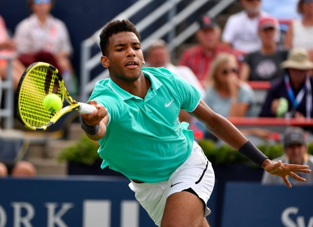 Felix Auger-Aliassime stretching for a shot in teal Nike polo on tennis court action wallpaper
