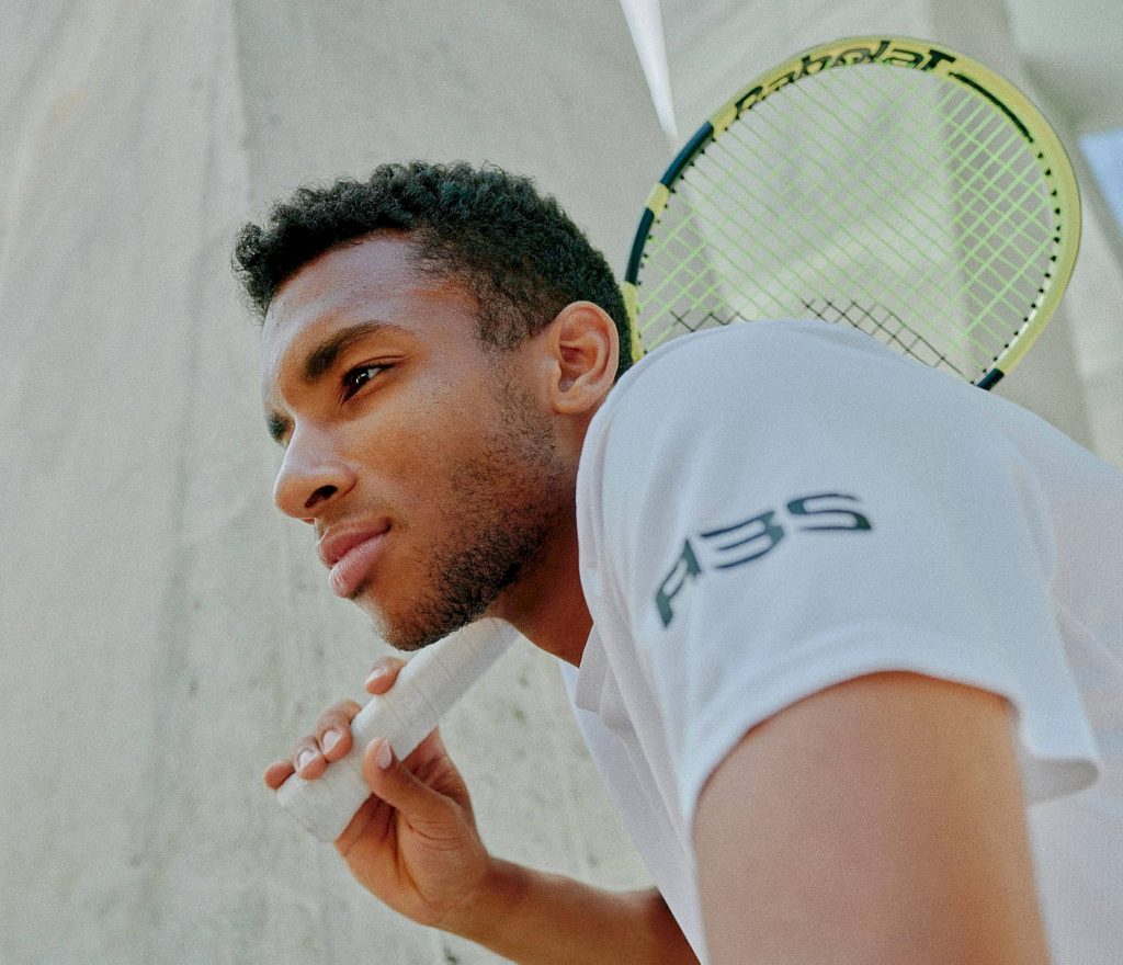 Félix Auger-Aliassime tennis portrait holding Babolat racket neutral textured background Wallpaper