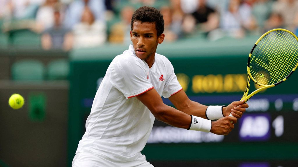 Tennis star Felix Auger-Aliassime mid-swing with yellow racket on green court sports wallpaper