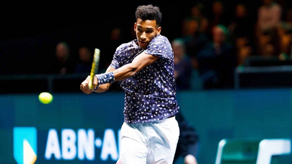 Félix Auger-Aliassime hitting two-handed backhand in high-energy tennis match action shot Wallpaper