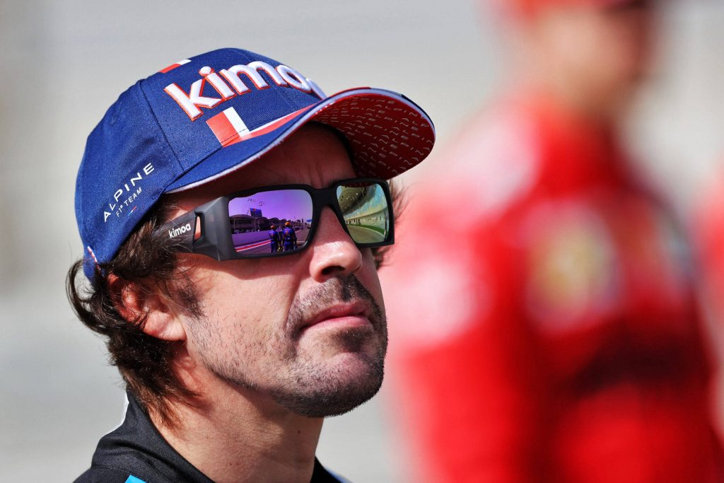 Close-up of F1 champion Fernando Alonso in Alpine cap with racetrack reflection in sunglasses Wallpaper