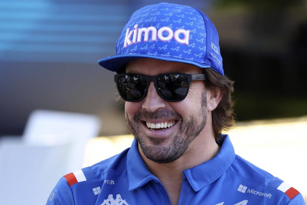 Formula 1 champion Fernando Alonso in blue Kimoa cap and Alpine polo smiling with sunglasses Wallpaper