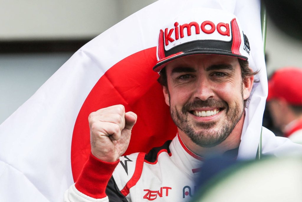 Fernando Alonso smiling in racing gear raising fist with Japanese flag background wallpaper