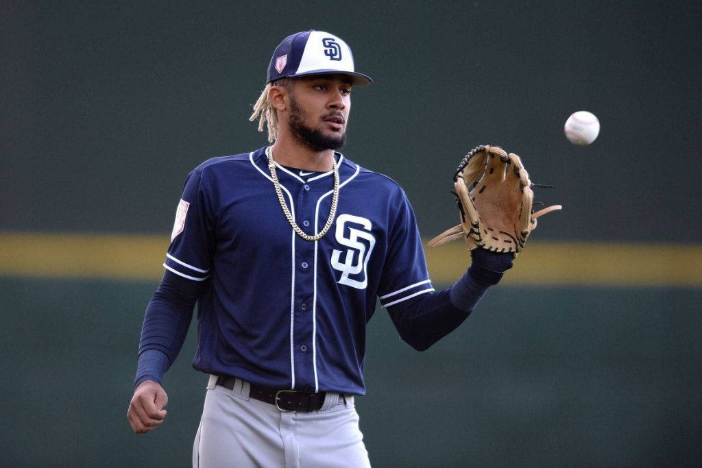 Fernando Tatís Jr. in navy Padres uniform catching baseball with green background wallpaper