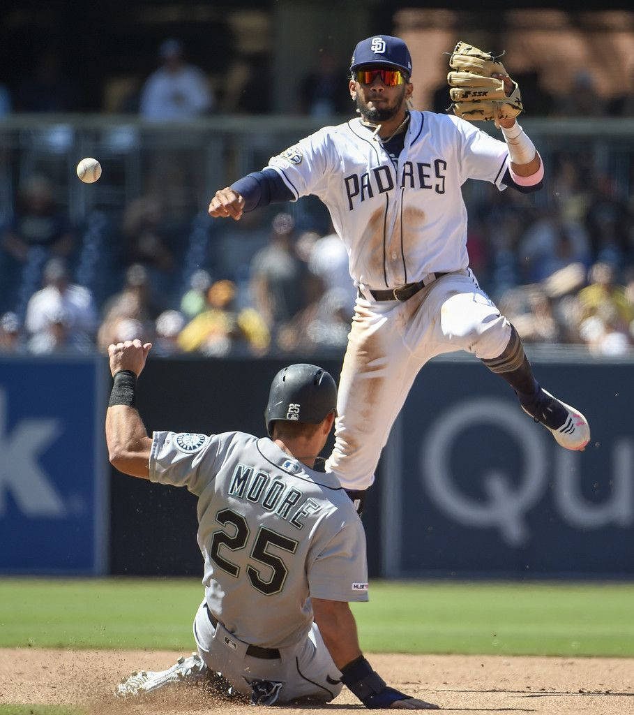 Fernando Tatis Jr leaping over Dylan Moore in intense San Diego Padres vs Seattle Mariners baseball play Wallpaper