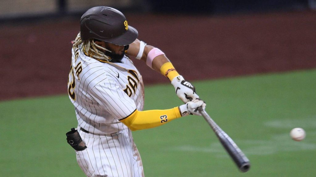 Fernando Tatís Jr. mid-swing in Padres pinstripe uniform hitting baseball powerful action shot Wallpaper