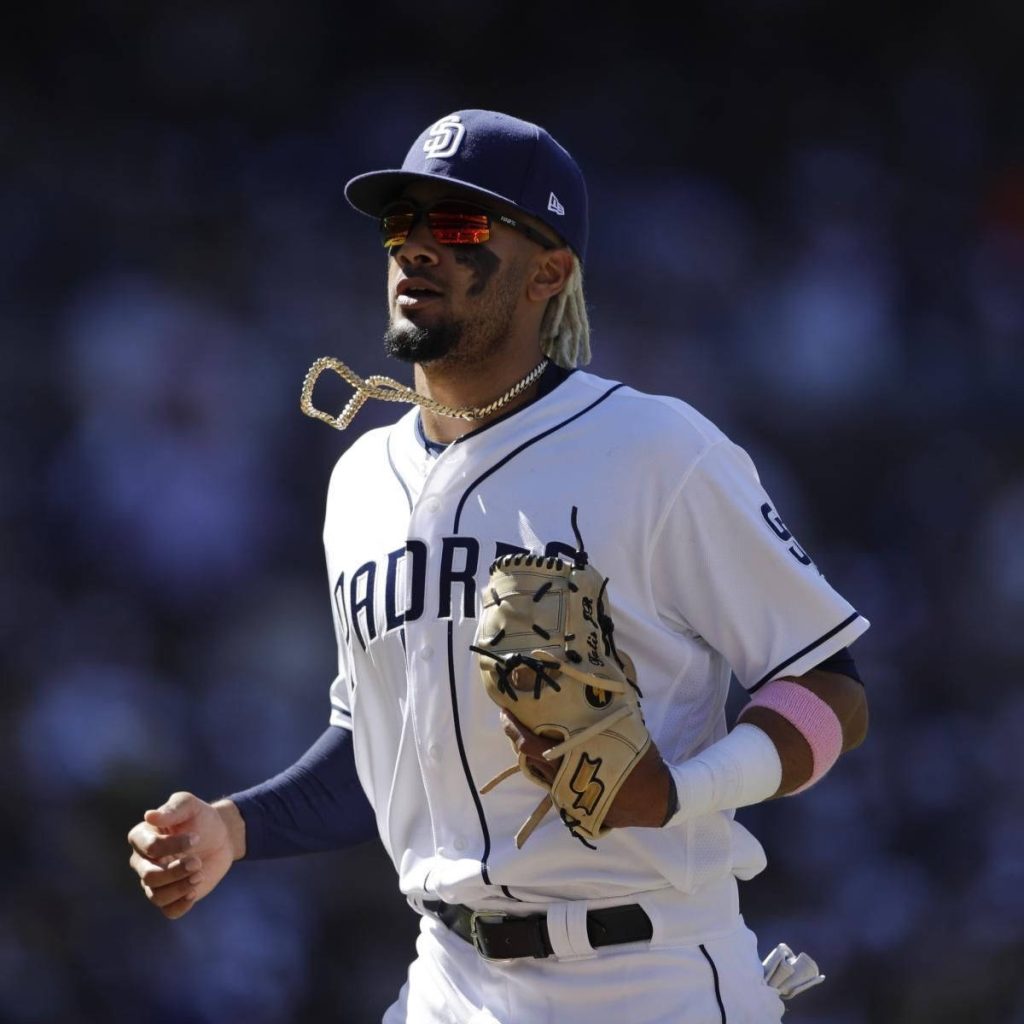 Fernando Tatis Jr. in Padres uniform mid-air catch with chain blurred stadium background wallpaper