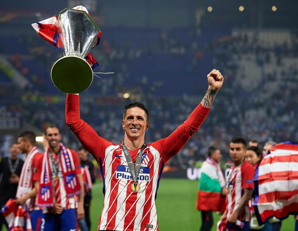 Fernando Torres lifting trophy in Atletico Madrid jersey celebrating football victory with teammates Wallpaper