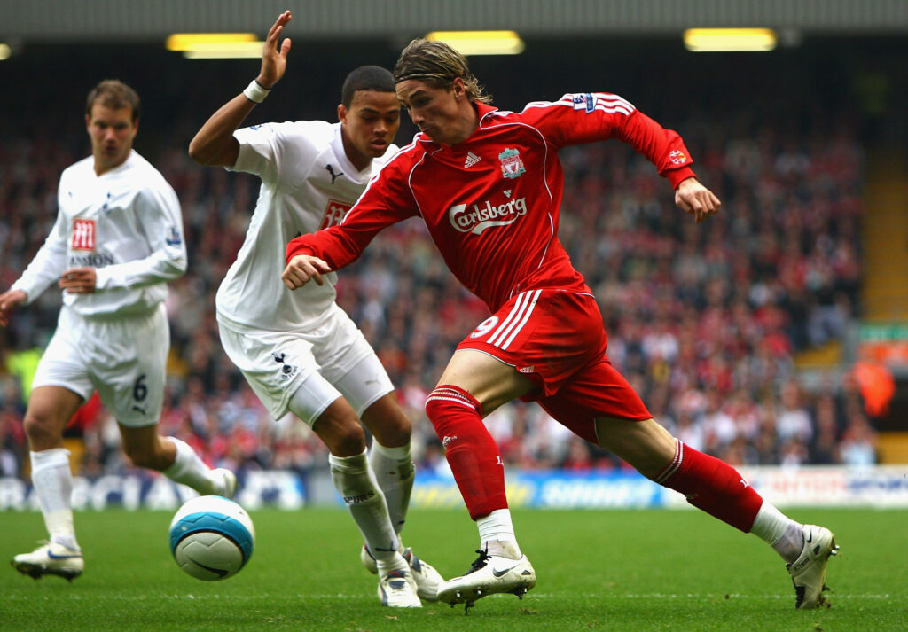Fernando Torres skillfully dribbling football in Liverpool kit showing determination on pitch Wallpaper