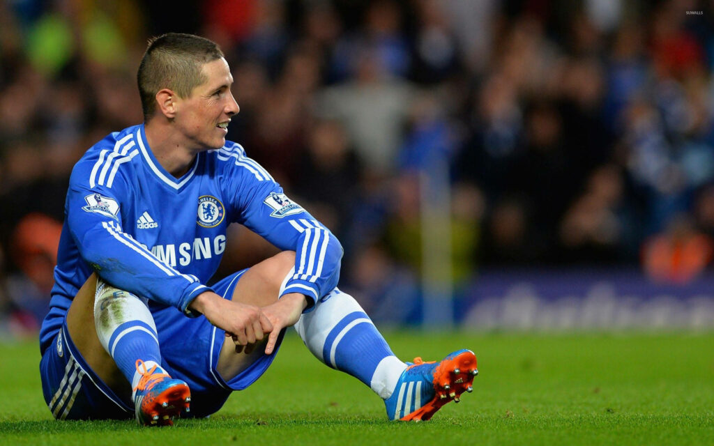 Fernando Torres sitting on soccer field in Chelsea kit reflecting during match wallpaper background