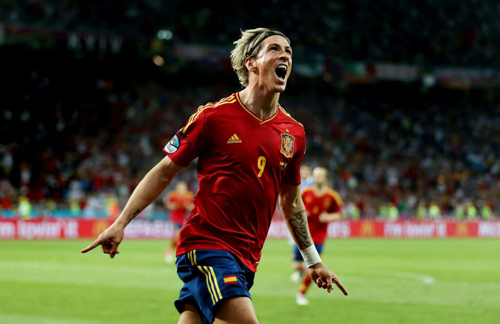 Fernando Torres celebrating in Spain jersey on bright football field during decisive game moment wallpaper