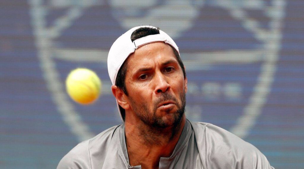 Tennis pro Fernando Verdasco in white cap hitting yellow ball with intense focus on court Wallpaper