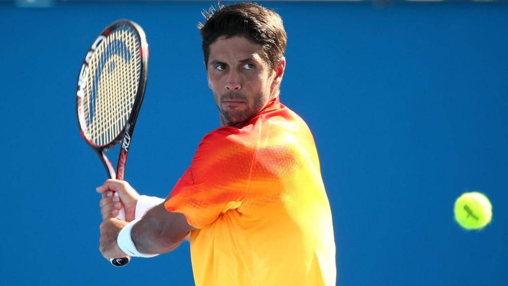 Fernando Verdasco in bright orange shirt hitting with HEAD racket on blue hard tennis court Wallpaper
