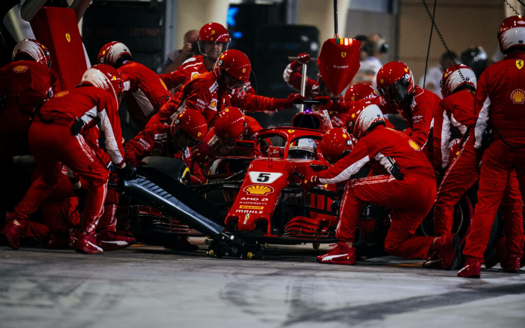 Revving Success: The Ferrari F1 2018 Resting in the Pit Stop, Awaiting Racing Prowess as Dedicated Crew Members Fine-tune the Beast on its Path to Victory Wallpaper