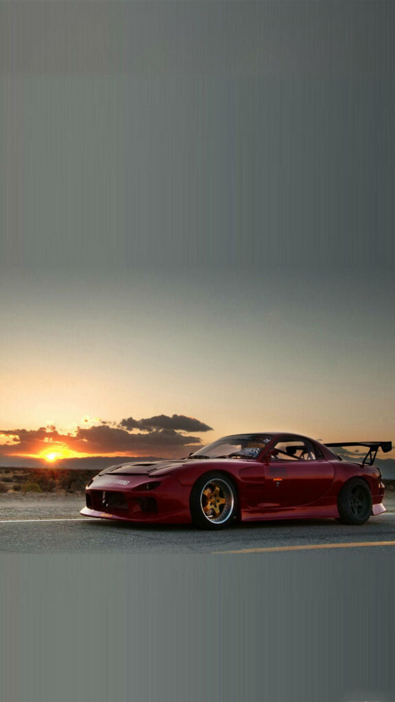 Ferrari F12 in sleek red parked on open road glowing under golden sunset perfect car wallpaper