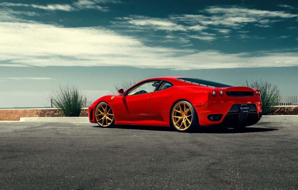The Ultimate Temptation: Exquisite Red Ferrari F430 on a Spectacular Sunlit Road, an Enthralling Display of Unmatched Performance for Sports Car Aficionados Wallpaper