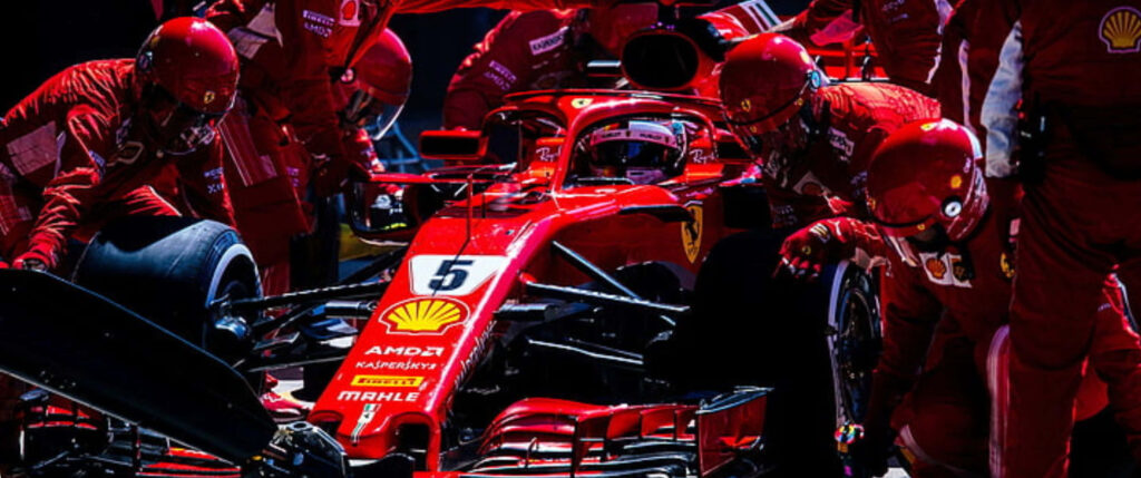 Ferrari Formula 1 car with red uniformed pit crew showcasing race day teamwork in pit lane Wallpaper