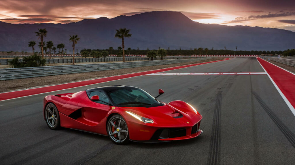 Ferrari LaFerrari on race track at sunset with mountains palm trees sleek red sports car Wallpaper