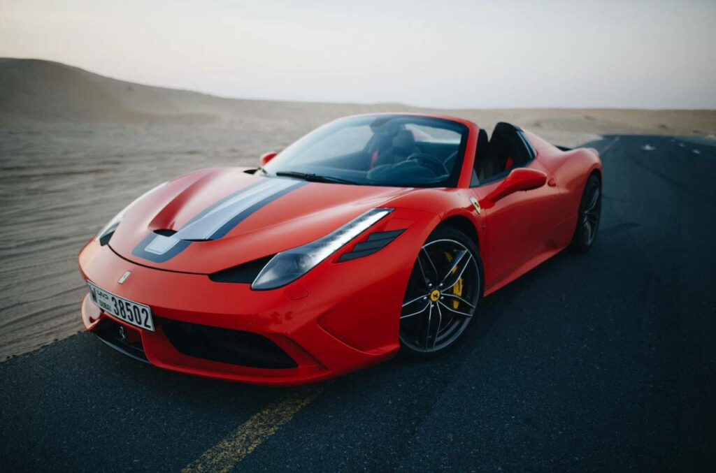 Red Ferrari Speciale with racing stripes parked on open desert road scenic wallpaper background