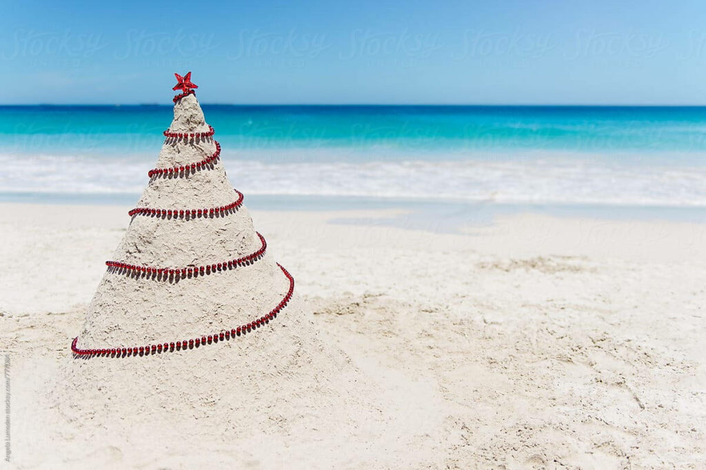 Festive Sandy Beach Christmas Tree Wallpaper with Ocean Backdrop
