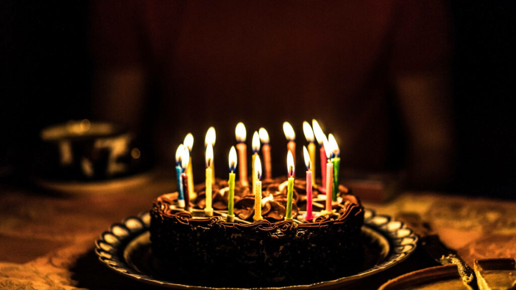 Festive Birthday Cake with Candles in a Warm Celebration Setting Wallpaper