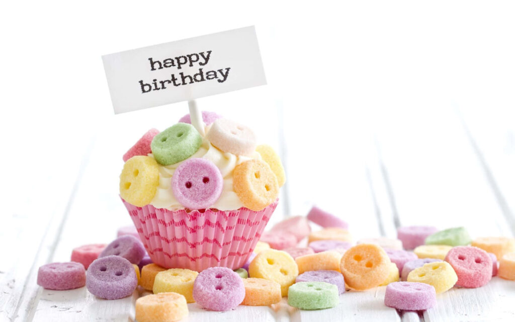 Festive Birthday Background with Cupcake and Colorful Cereal Rings Wallpaper