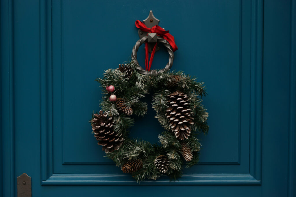 Festive Delight: Captivating Christmas Wreath Adorning a Vibrant Red Door Embraces Guests with Warmth and Joy Wallpaper