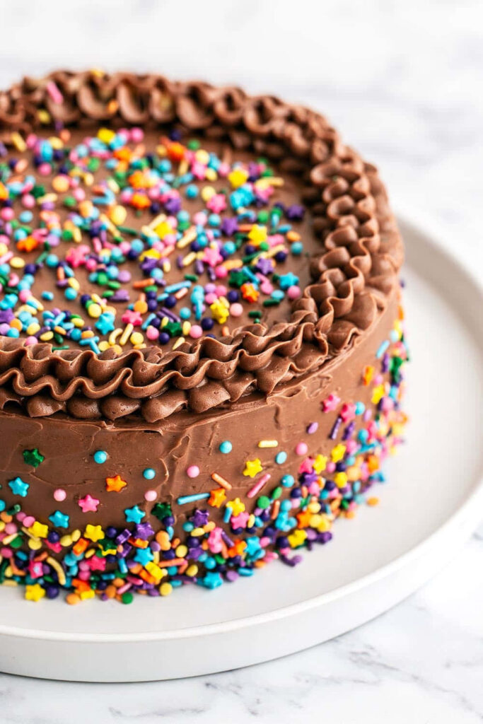 Festive Chocolate Cake Wallpaper with Colorful Sprinkles Background