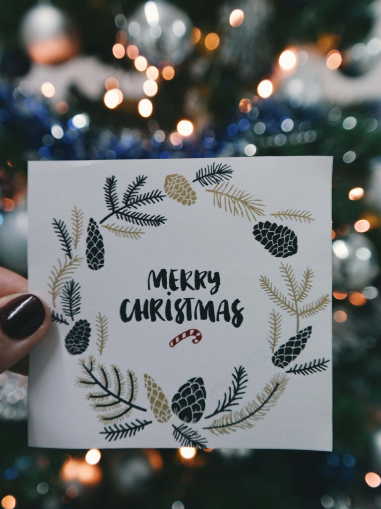 Festive Christmas Card with Wreath on Blurred Holiday Background Wallpaper