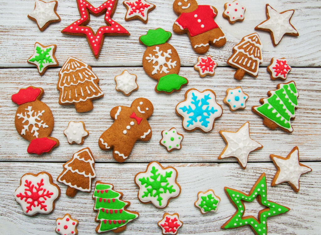 Festive Christmas cookies with colorful icing on rustic wood creating a cozy holiday vibe Wallpaper