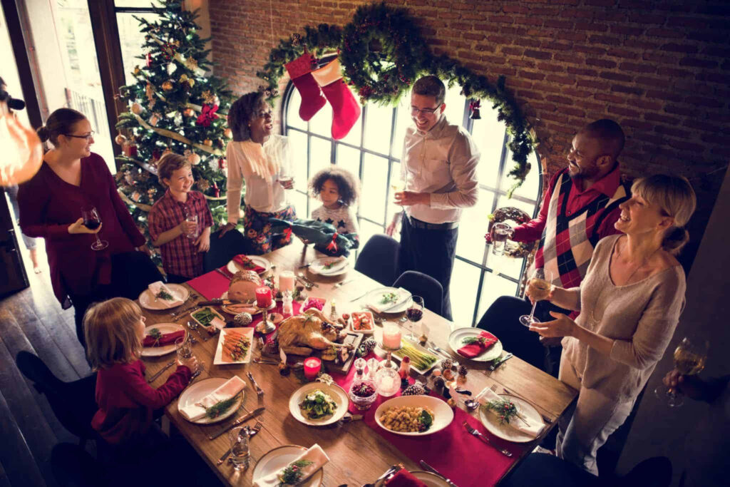 Festive Christmas Gathering Wallpaper: Joyful Holiday Meal Scene