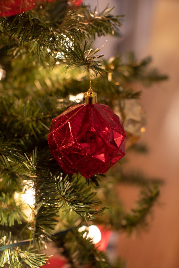 Festive Christmas Ornament on Green Branch - Holiday Cheer Background Wallpaper