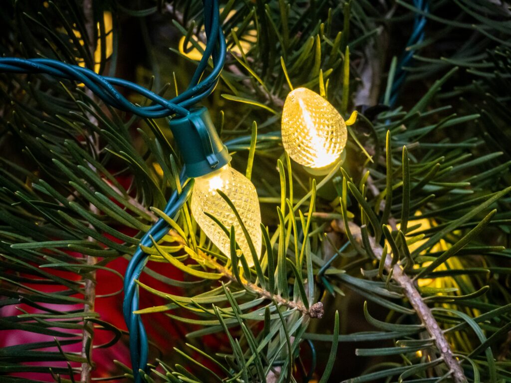 Festive Close-Up: Christmas Tree Branches with Glowing Yellow Lights Wallpaper