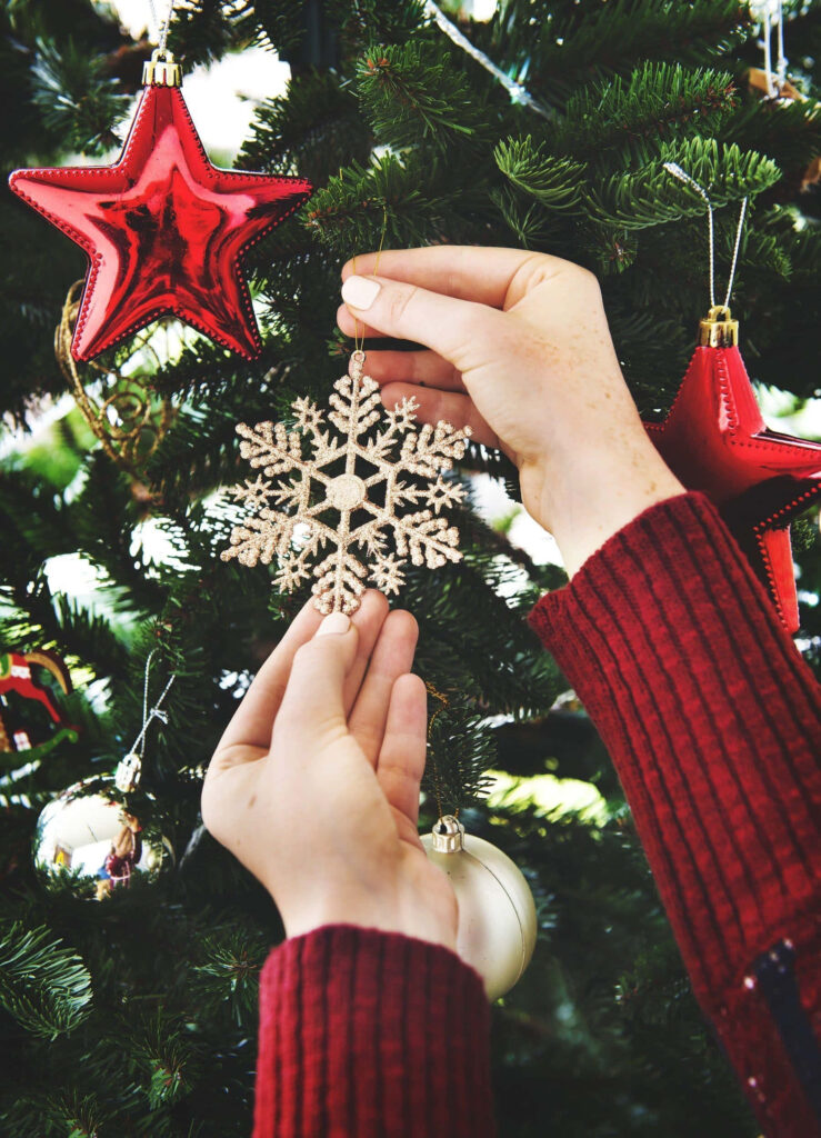 Christmas Tree Decorating with Snowflake and Star Ornaments Wallpaper