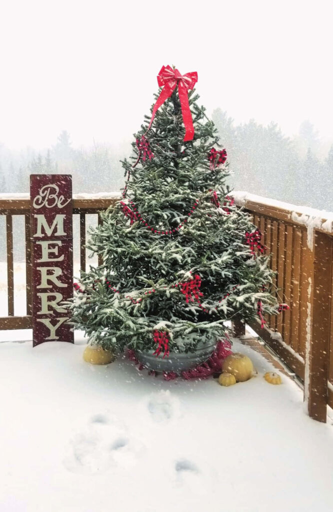 Festive Christmas Tree on Snowy Deck with Be Merry Sign Wallpaper