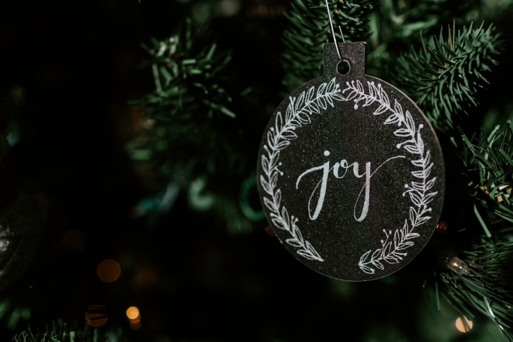 Festive Christmas Tree Close-Up: Joy Ornament & Wreath Background Wallpaper