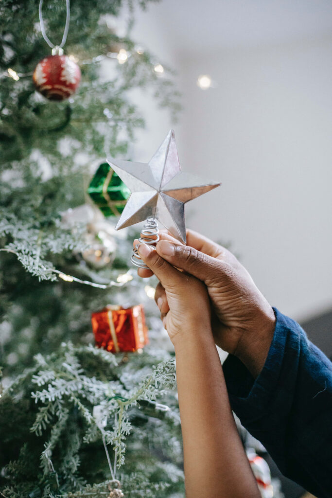 Hand Holding Silver Star Ornament for Festive Christmas Tree Wallpaper
