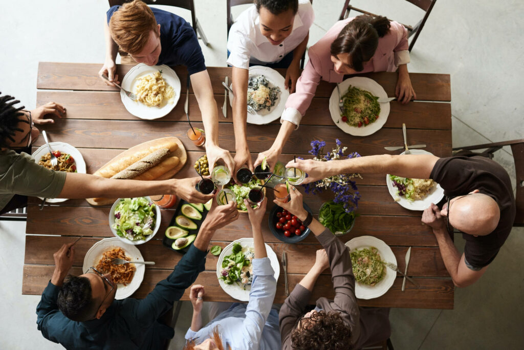 Dinner Celebration: Friends Toasting Around a Wooden Table Wallpaper