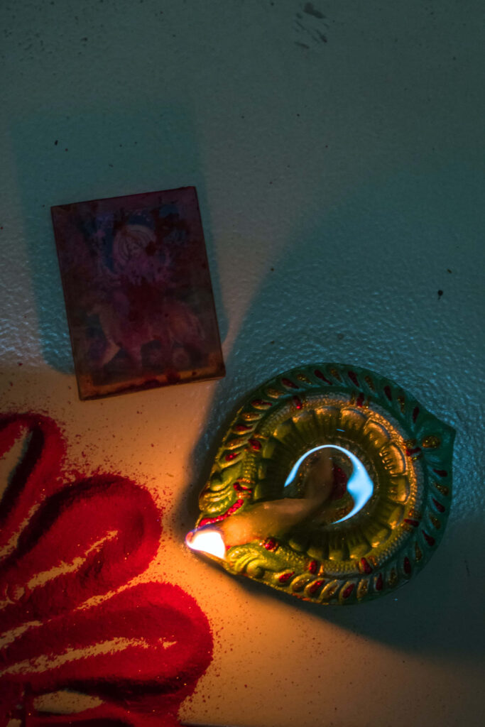 Traditional Diwali celebration with glowing oil diya red rangoli and devotional image wallpaper