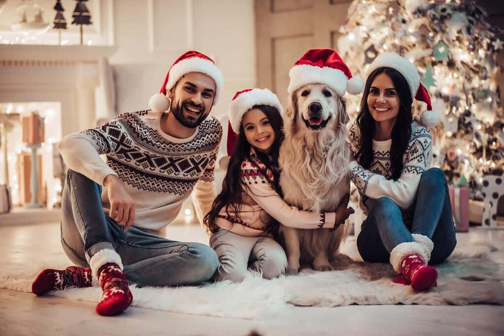 Joyful Christmas Family Scene with Golden Retriever by Tree Wallpaper