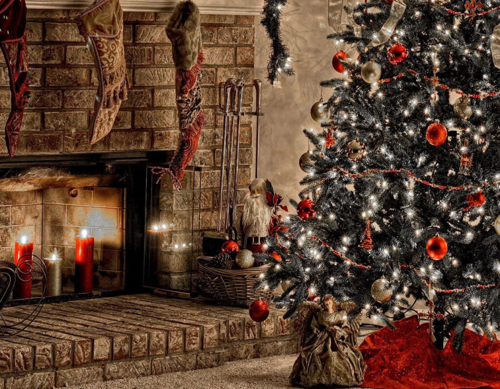 Festive Fireplace Delight: Cozy Yuletide Ambiance with Hanging Stockings and a Christmas Tree Wallpaper