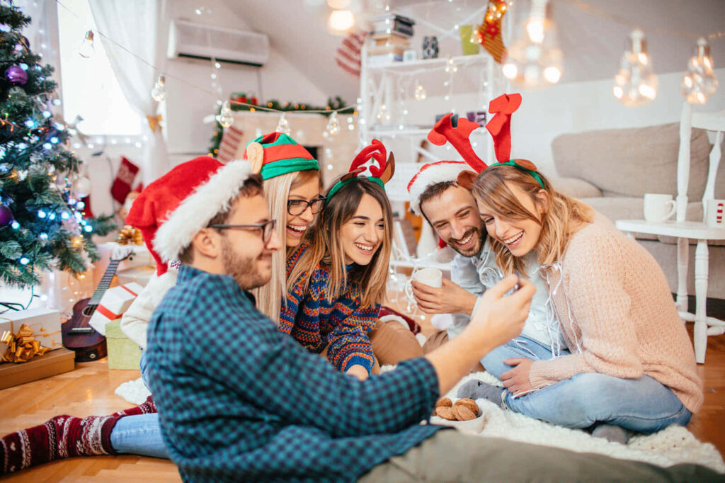 Joyful Friends in Santa Hats Celebrate Christmas in a Festive Room Wallpaper