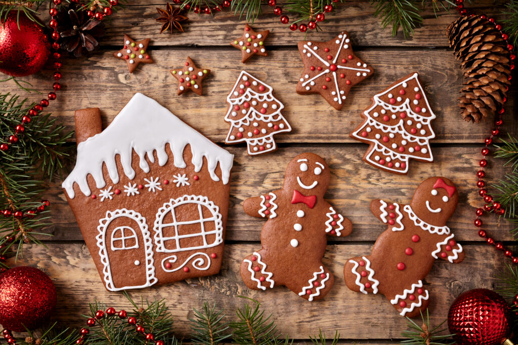 Festive gingerbread cookies house Christmas trees stars on wooden background with pine branches Wallpaper