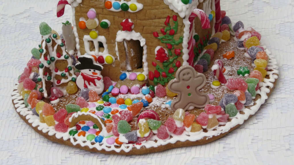 Festive wallpaper with gingerbread house smiling gingerbread man and cheerful snowman holiday scene
